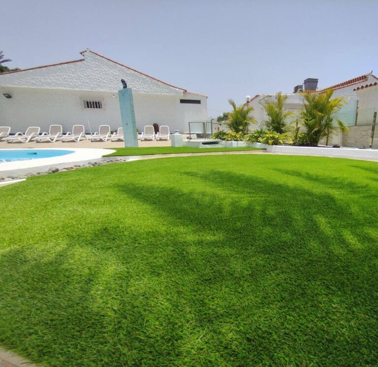 Zona de piscina con tumbonas sobre césped artificial en Las Palmas